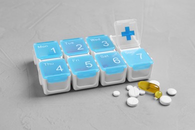 Weekly pill box with medicaments on grey table