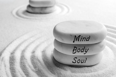 Image of Stones with words Mind, Body, Soul on sand, space for text. Zen and harmony 