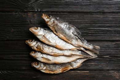 Tasty dried fish on black wooden table, flat lay