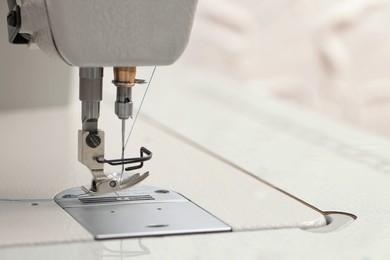 Photo of Modern sewing machine on blurred background, closeup. Space for text