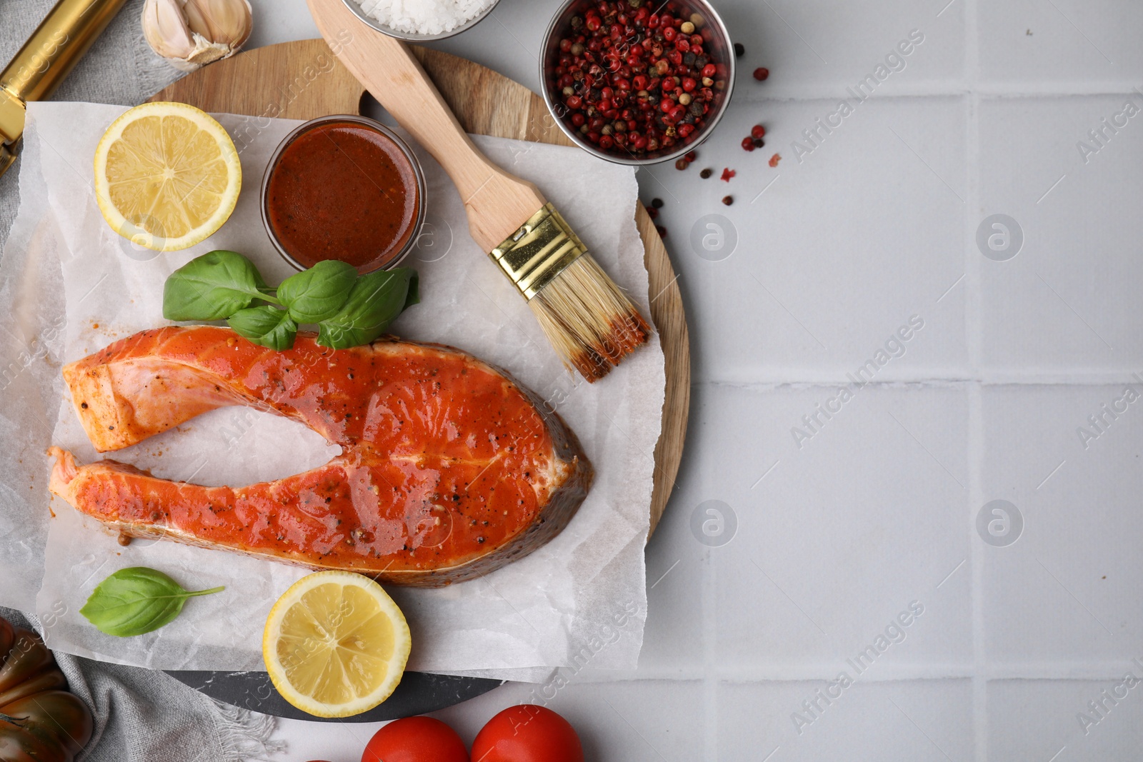 Photo of Fresh marinade, fish, lemon, brush and basil on white tiled table, flat lay. Space for text