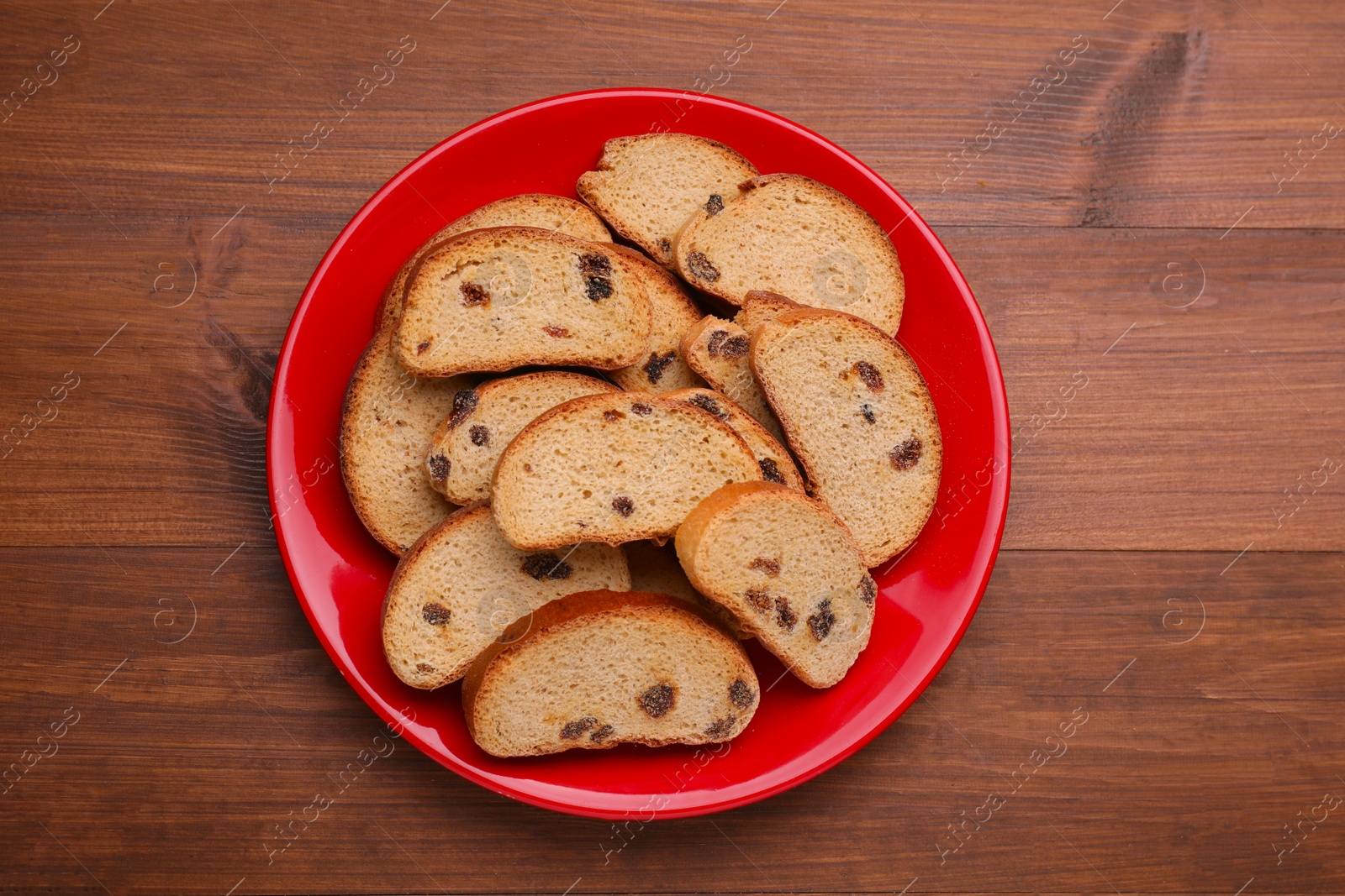 Photo of Plate of sweet hard chuck crackers with raisins on wooden table, top view