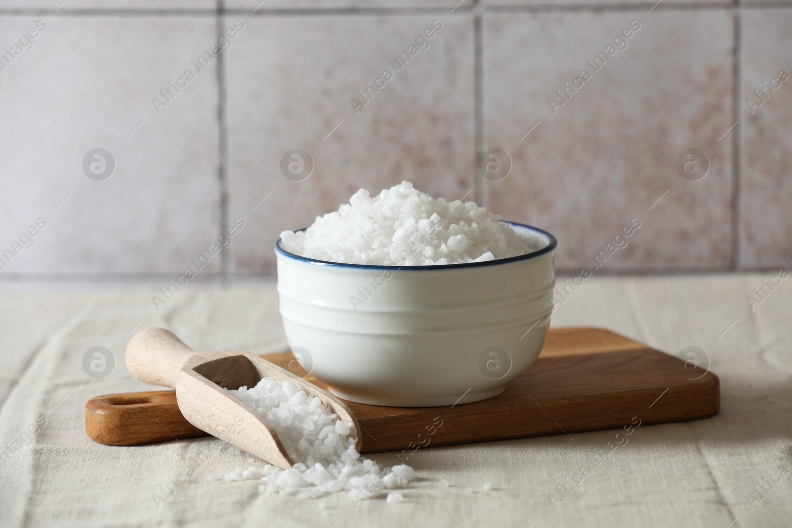 Photo of Organic salt in bowl and scoop on table