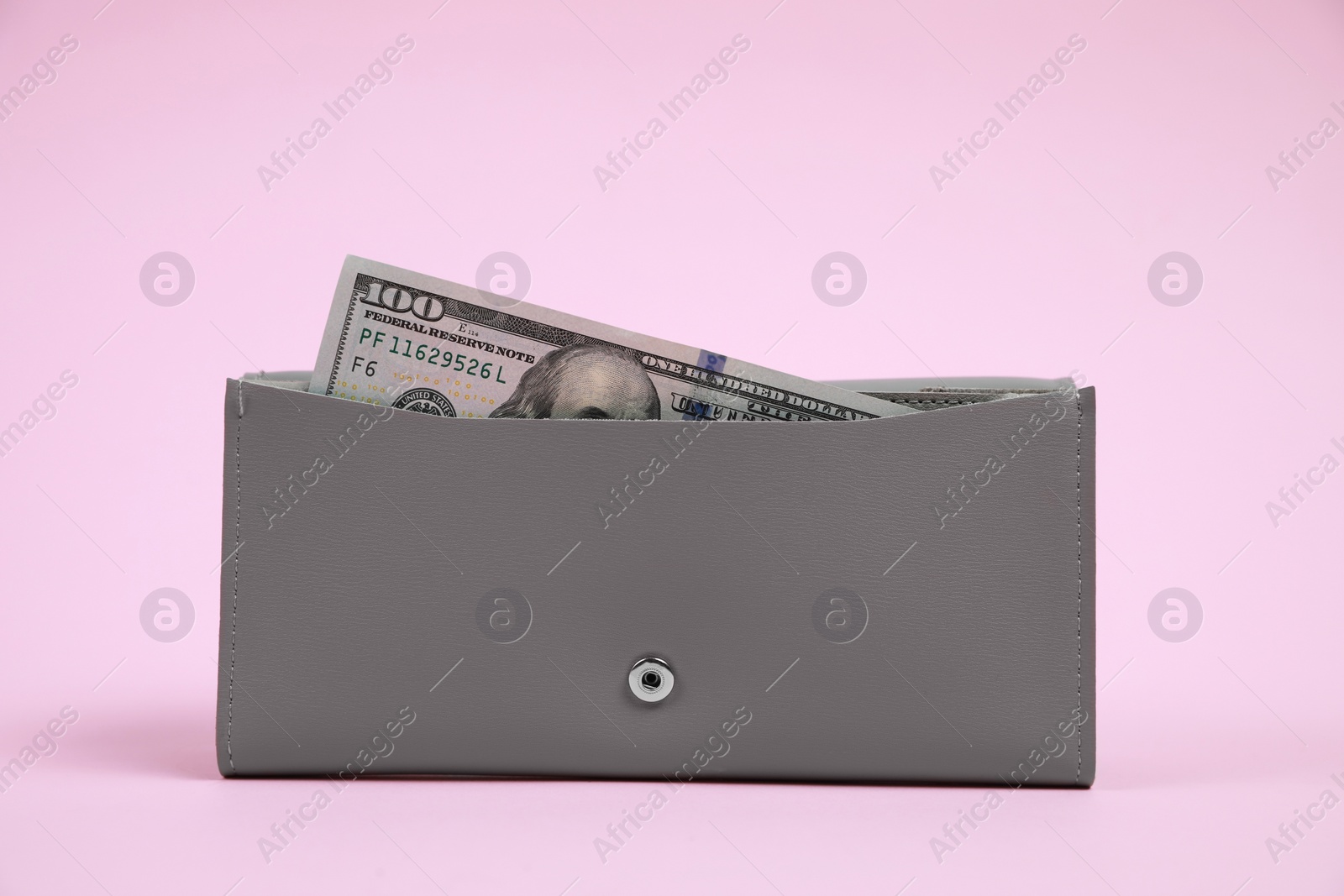 Photo of Stylish grey leather purse with dollar banknote on pink background
