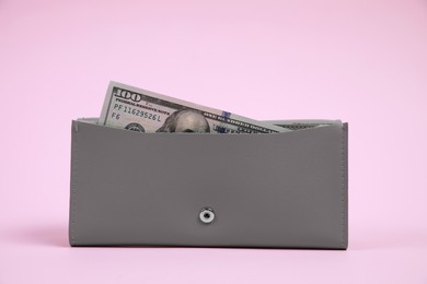 Stylish grey leather purse with dollar banknote on pink background