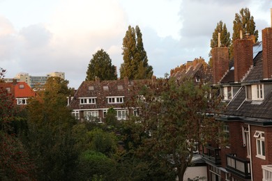 Beautiful buildings and trees in city under sky with clouds