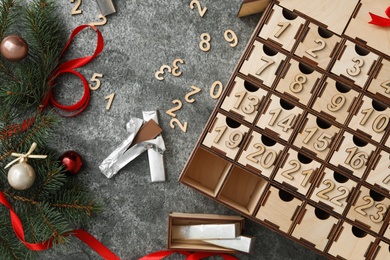 Photo of Flat lay composition with wooden advent calendar and Christmas decor on grey background