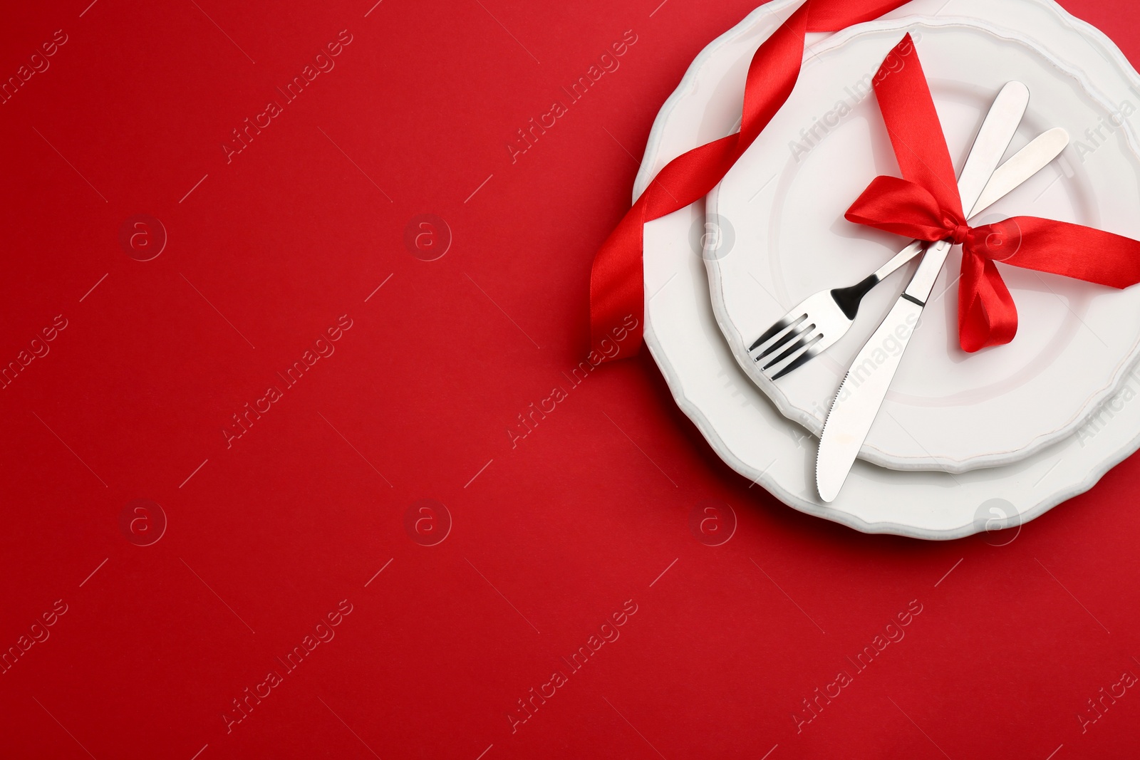 Photo of Beautiful table setting on red background, top view with space for text. Valentine's Day dinner