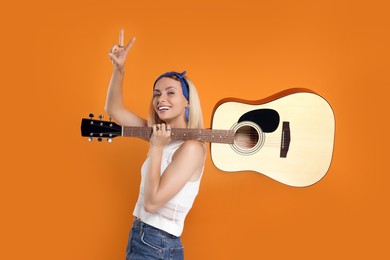 Photo of Happy hippie woman with guitar showing peace sign on orange background
