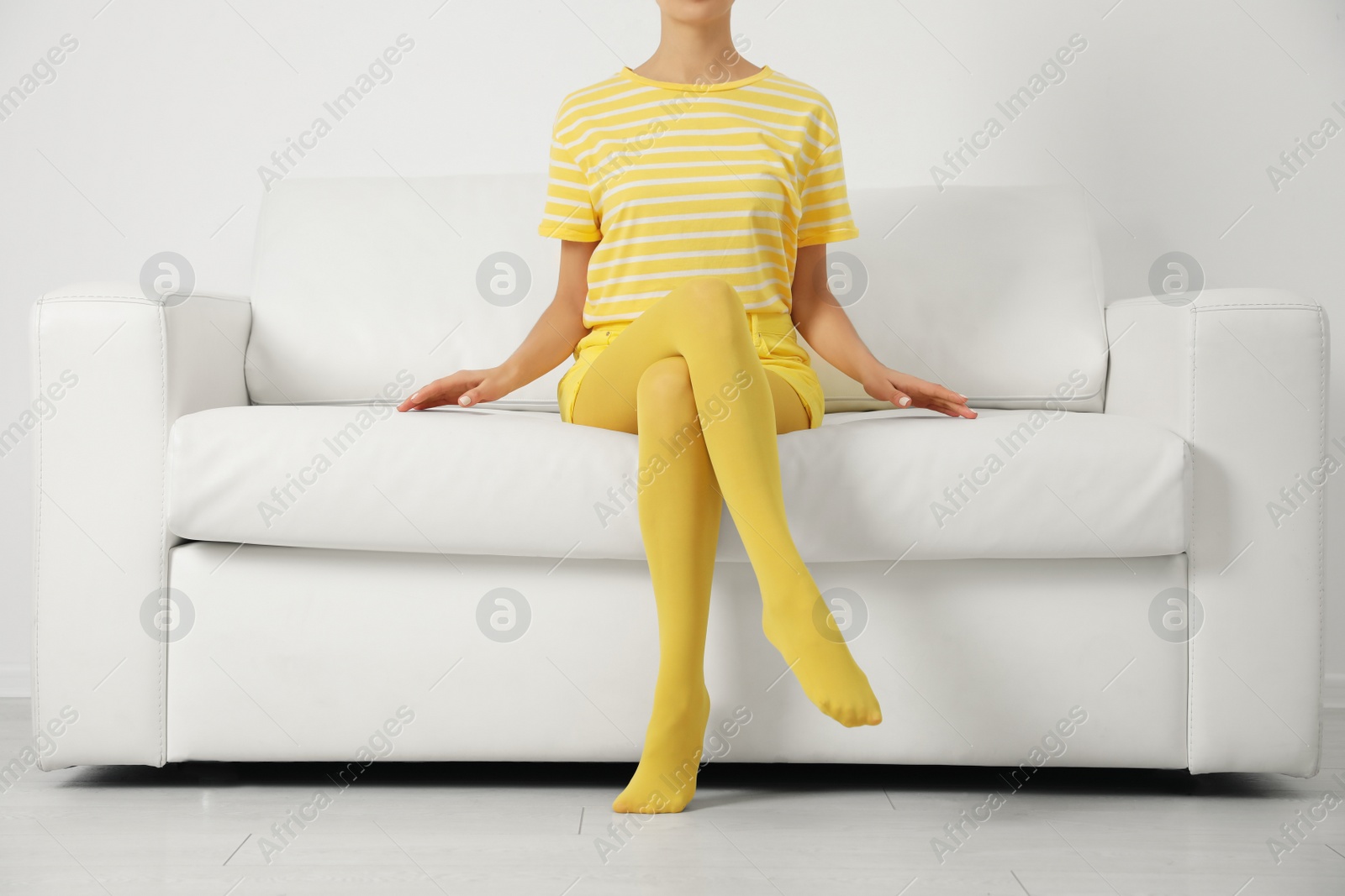 Photo of Woman wearing yellow tights sitting on sofa indoors, closeup