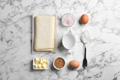 Photo of Flat lay composition of puff pastry dough and ingredients on white marble table