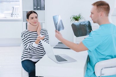 Doctor with neck MRI images consulting patient in clinic