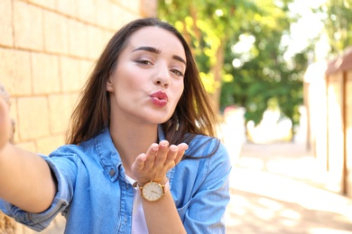 Young woman taking selfie outdoors on sunny day