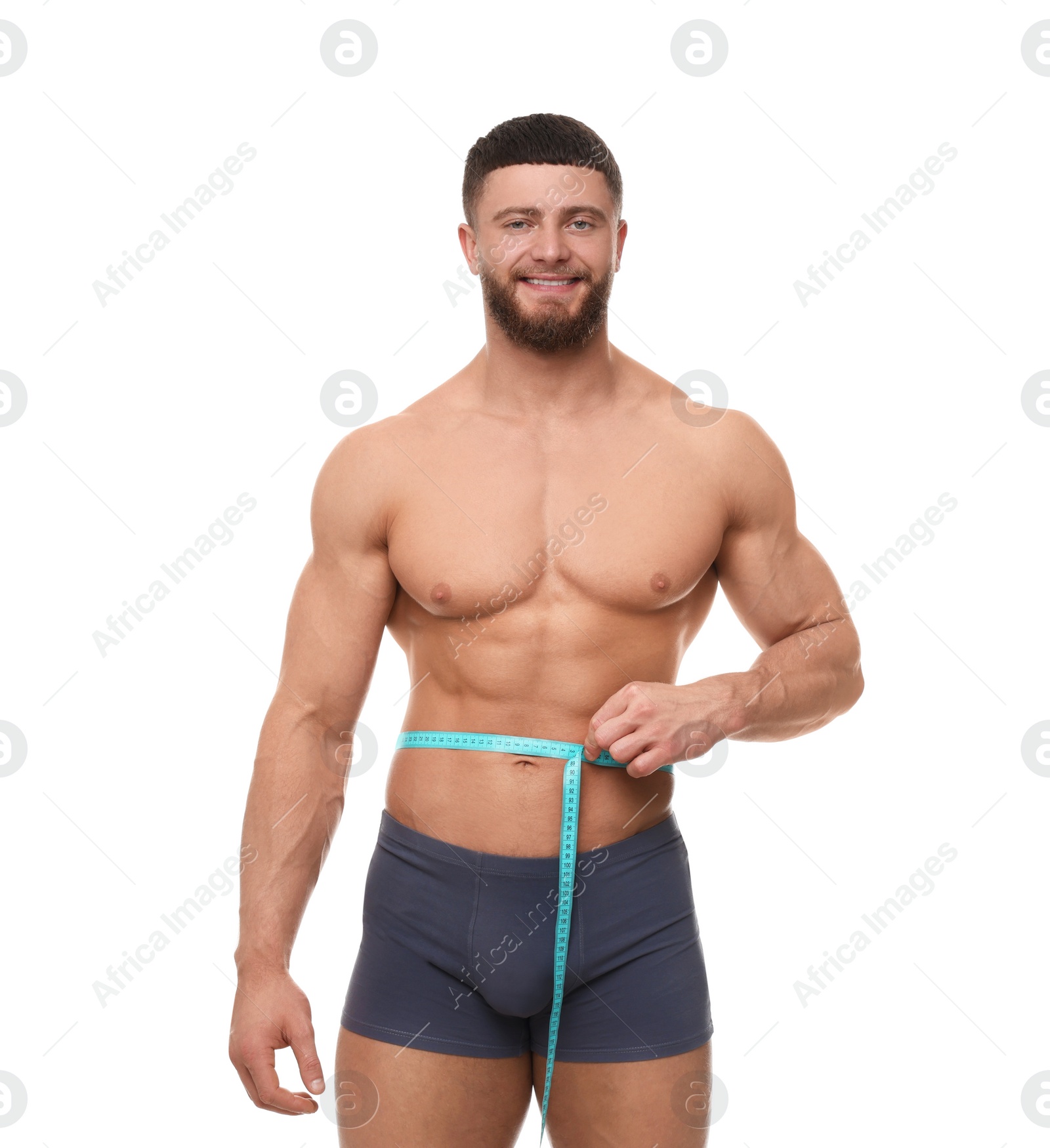 Photo of Portrait of happy athletic man measuring waist with tape on white background. Weight loss concept