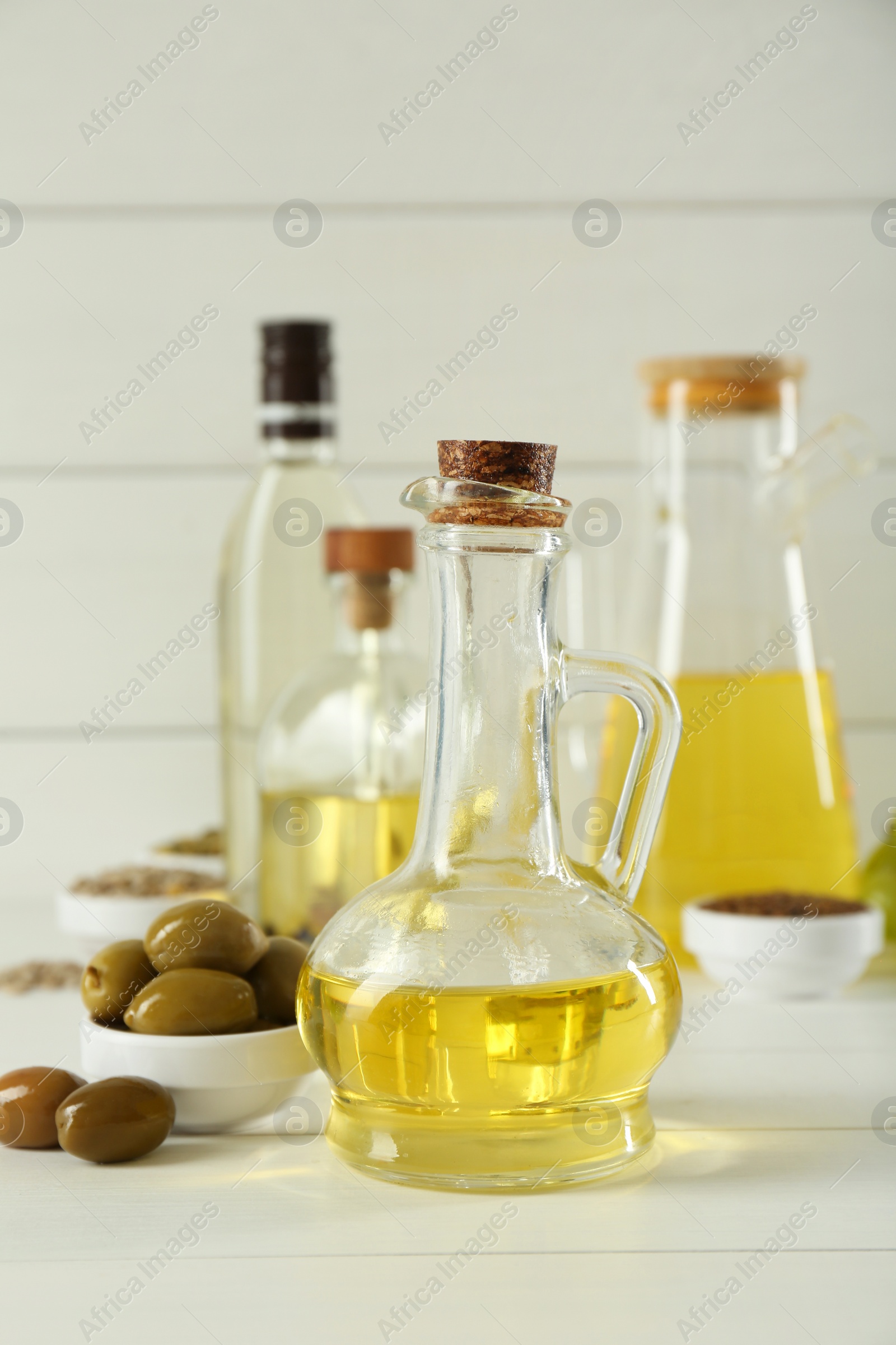 Photo of Vegetable fats. Different cooking oils in bottles and ingredients on white wooden table