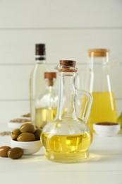 Photo of Vegetable fats. Different cooking oils in bottles and ingredients on white wooden table