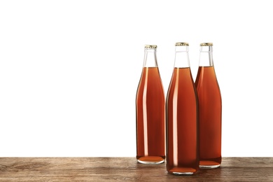 Photo of Bottles of delicious kvass on wooden table against white background