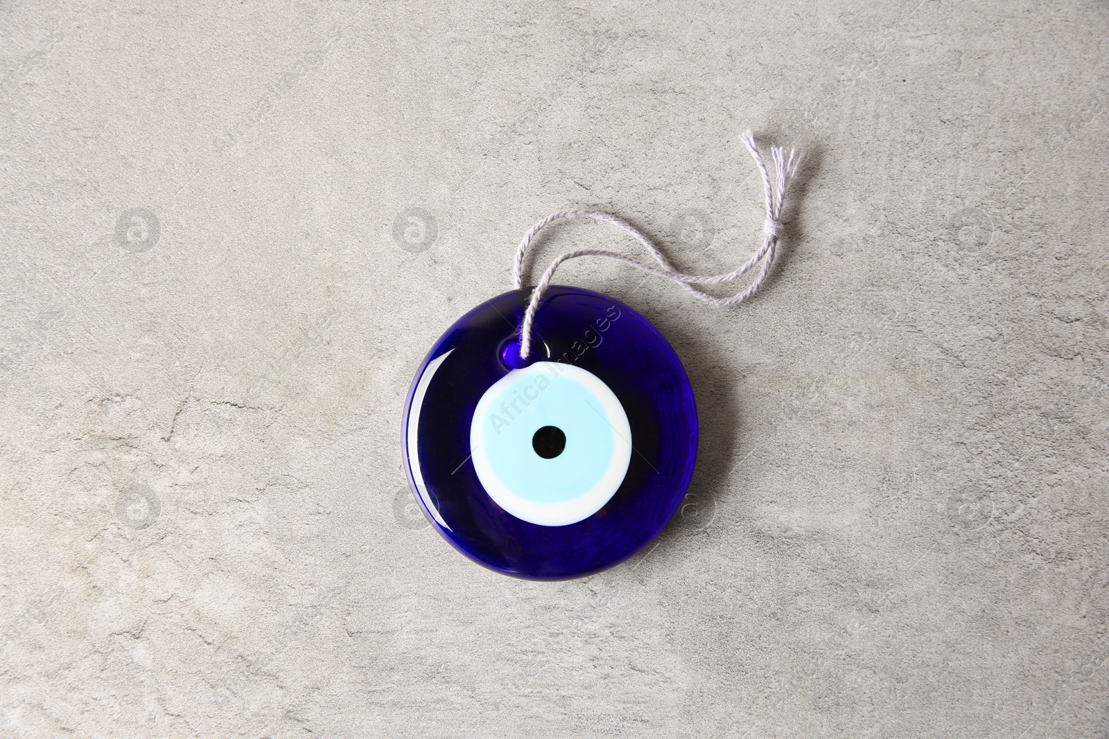 Photo of Evil eye amulet on light grey table, top view