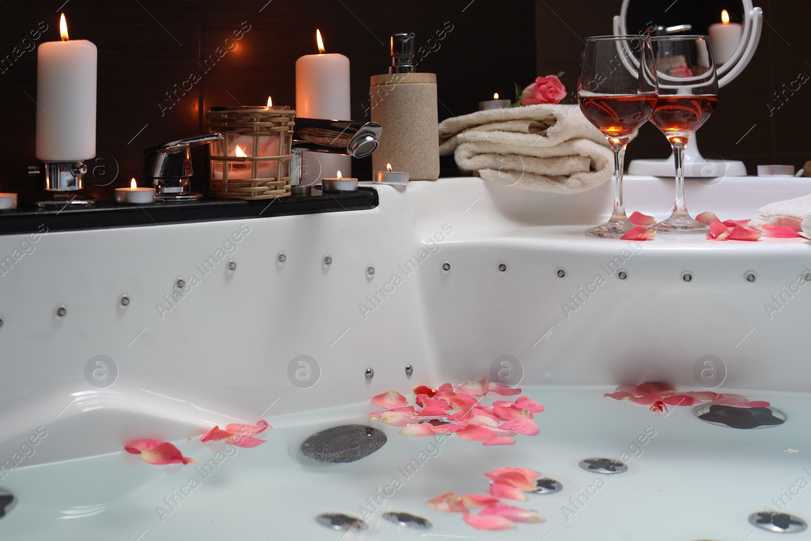 Photo of Bathtub with glasses of wine and candles indoors. Romantic atmosphere