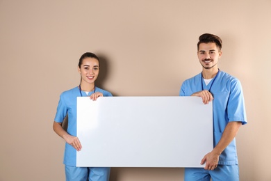 Photo of Medical students with blank poster on color background. Space for text