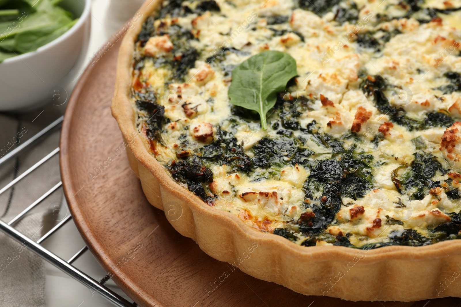 Photo of Delicious homemade spinach quiche on wooden board, closeup