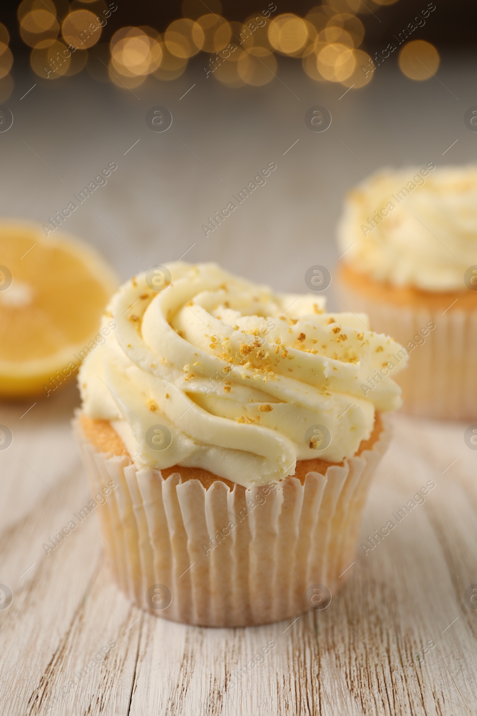 Photo of Tasty cupcake with cream and lemon zest on white wooden table, closeup