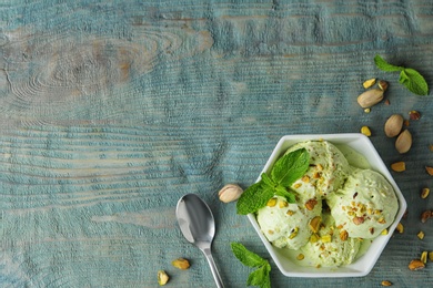 Photo of Delicious pistachio ice cream on blue wooden table, flat lay. Space for text