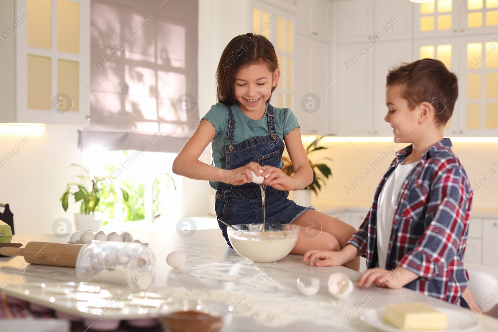 Photo of Cute little children cooking dough in kitchen at home