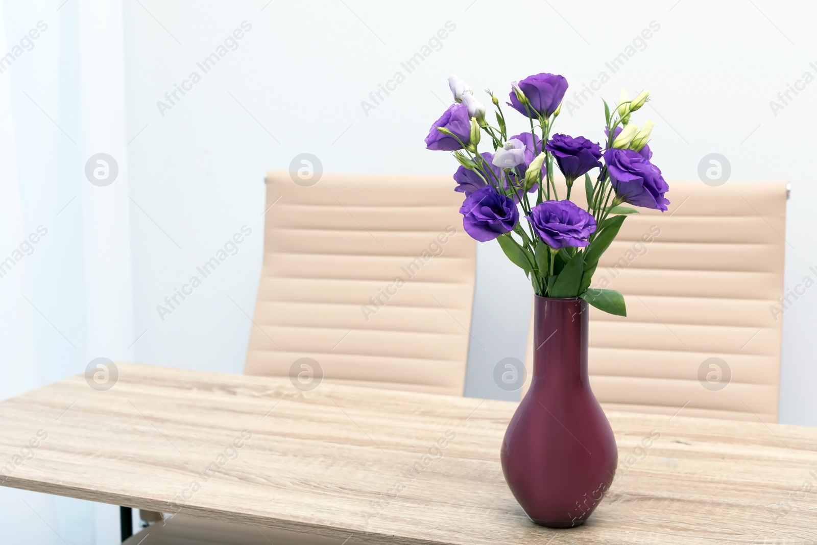 Photo of Beautiful bouquet in vase on wooden table against color background. Stylish interior