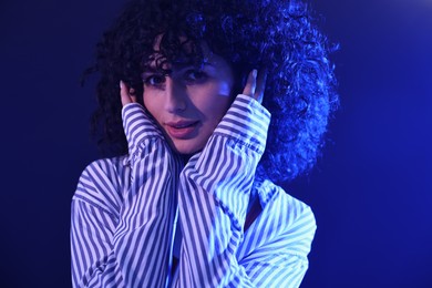 Beautiful young woman posing on color background in neon lights, closeup