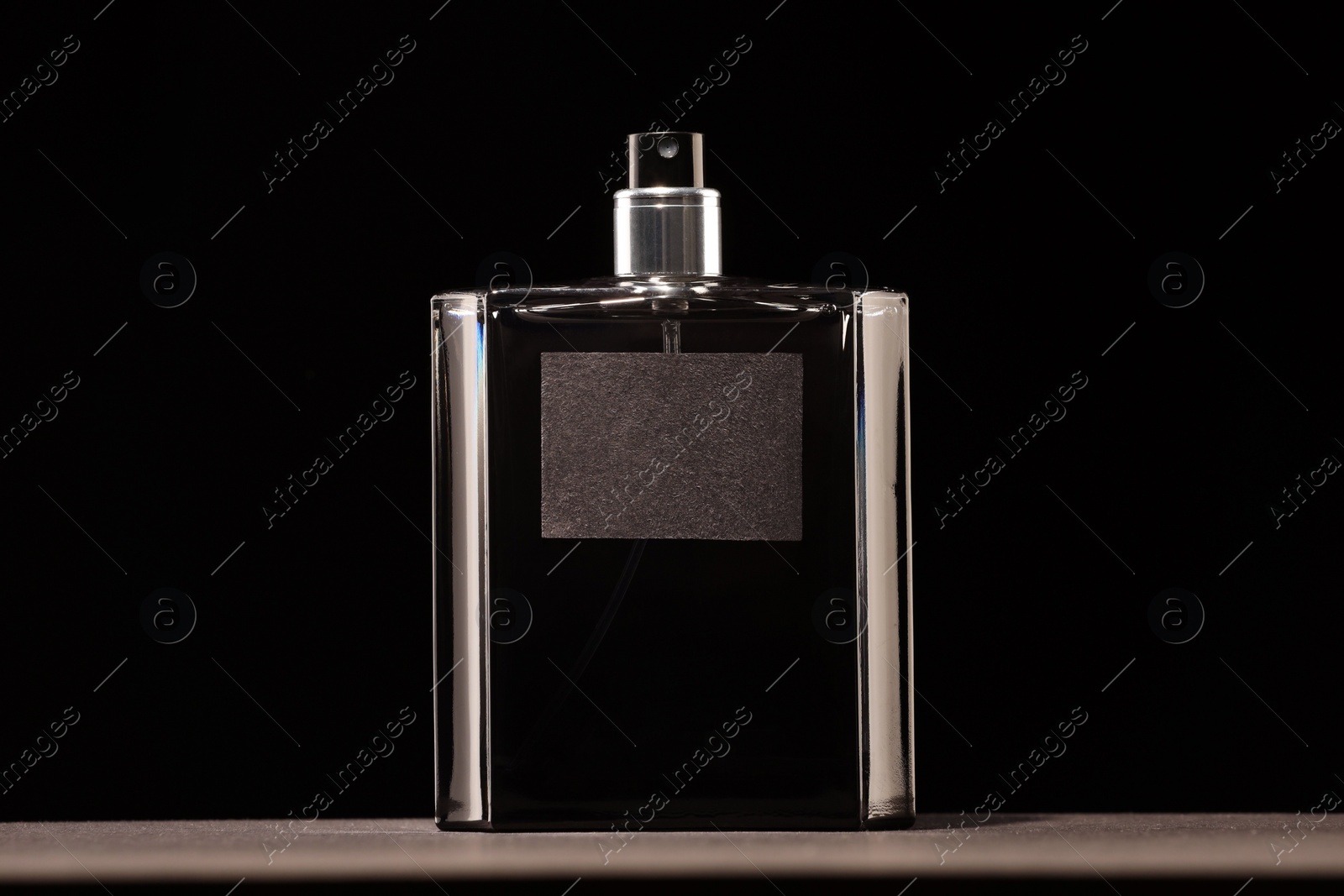 Photo of Luxury men`s perfume in bottle on grey table against black background