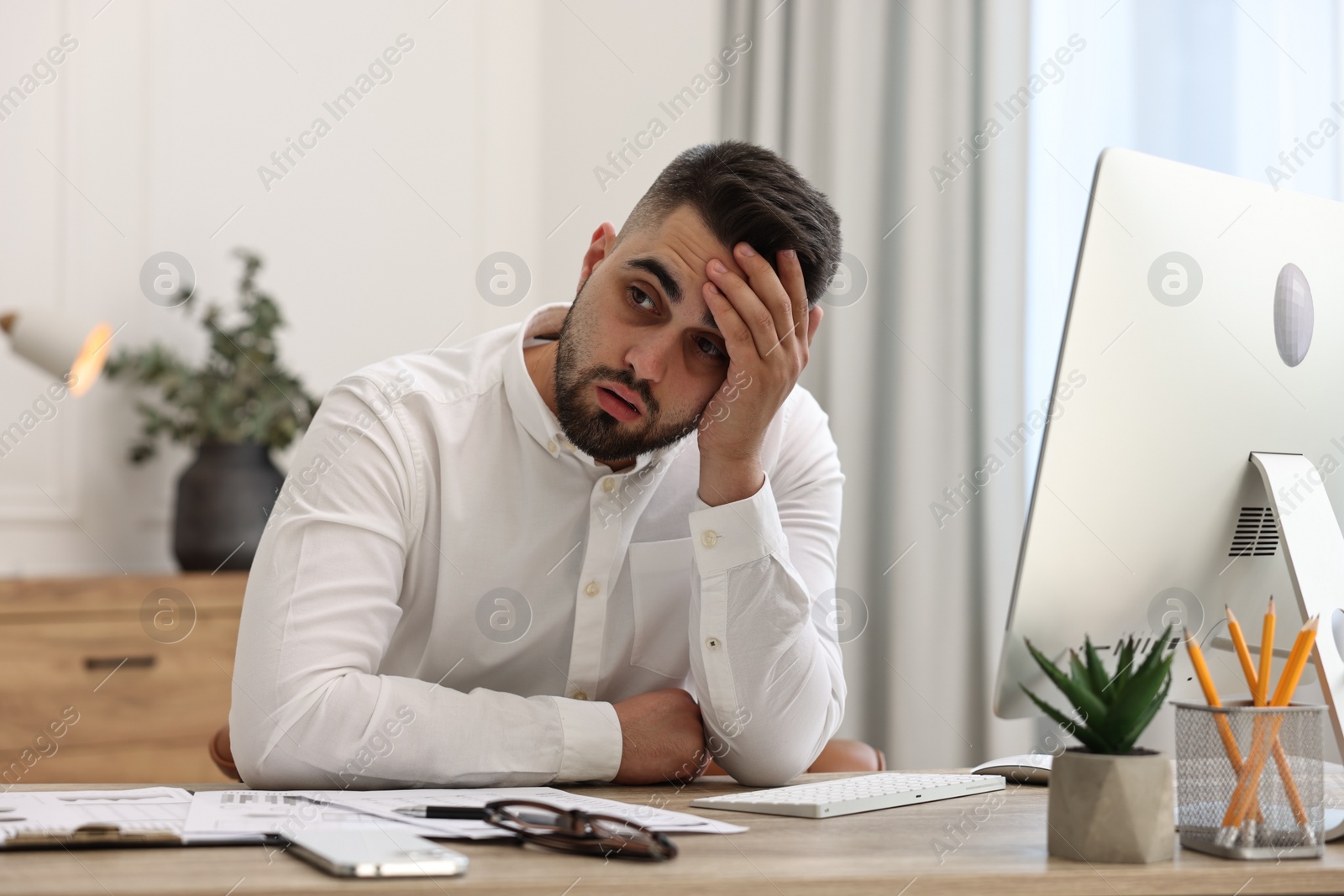 Photo of Overwhelmed man sitting at table in office