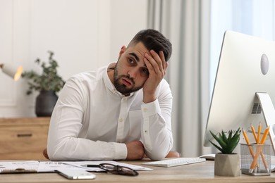 Overwhelmed man sitting at table in office