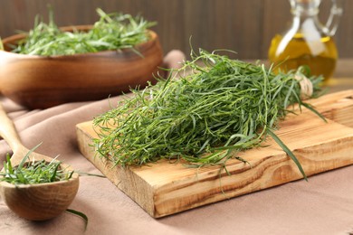 Photo of Fresh green tarragon sprigs on pink tablecloth