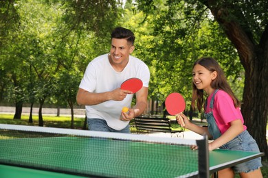 Photo of Happy man with his daughter playing ping pong in park