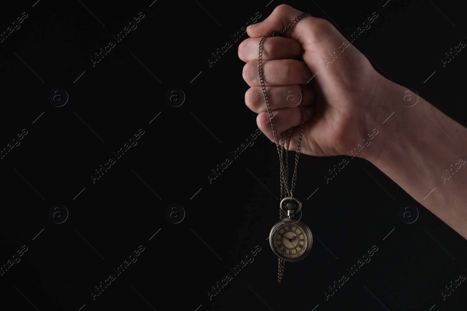 Photo of Man holding chain with elegant pocket watch on black background, closeup. Space for text