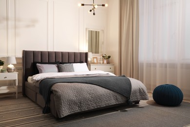 Stylish bedroom interior with large comfortable bed and chest of drawers