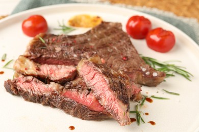 Photo of Delicious grilled beef steak, tomatoes and rosemary on plate, closeup