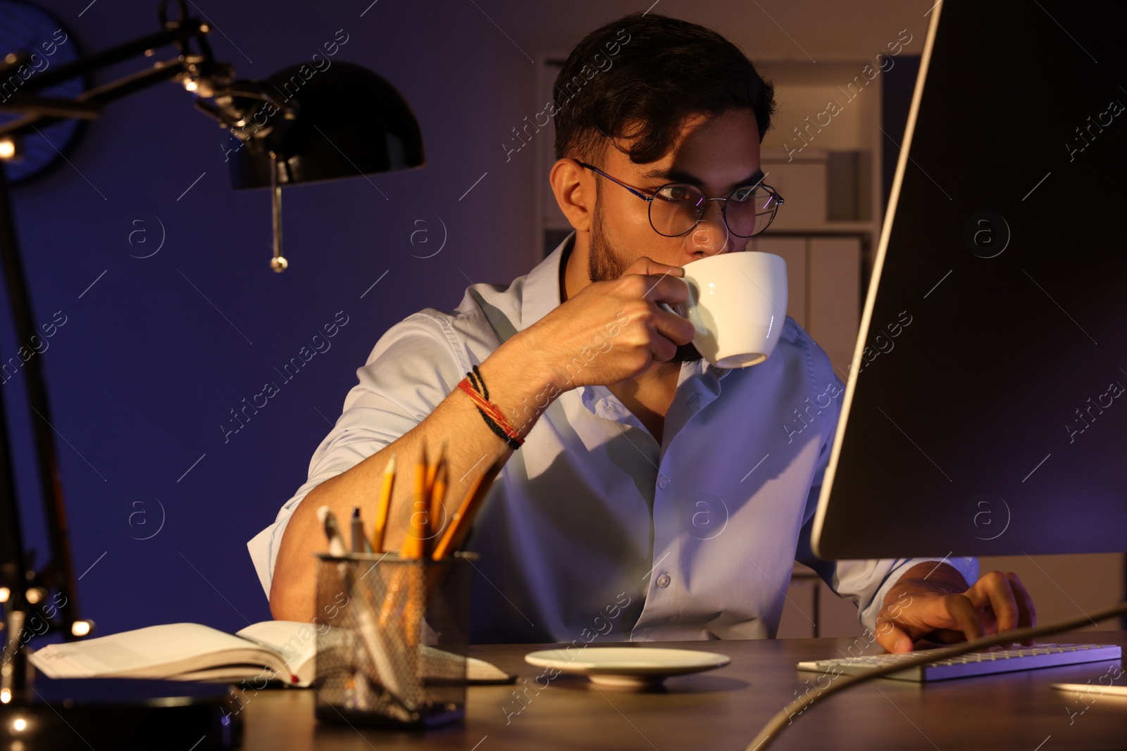 Photo of Tired man with coffee working late in office