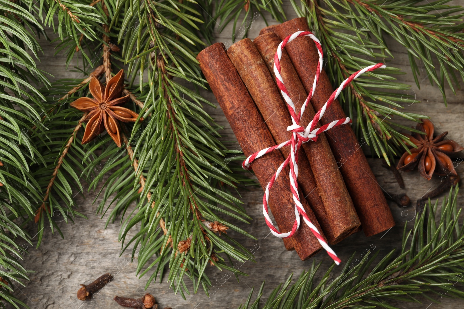 Photo of Different spices and fir branches on wooden table, flat lay