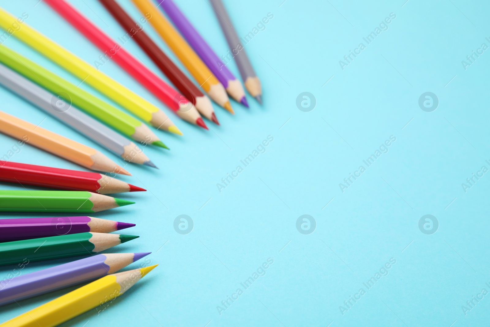 Photo of Colorful wooden pencils on light blue background, above view. Space for text