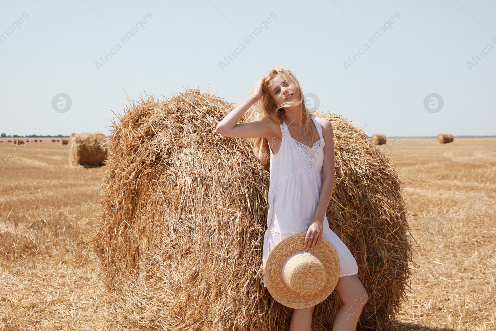 Photo of Beautiful young woman with straw hat near rolled hay bale on sunny day