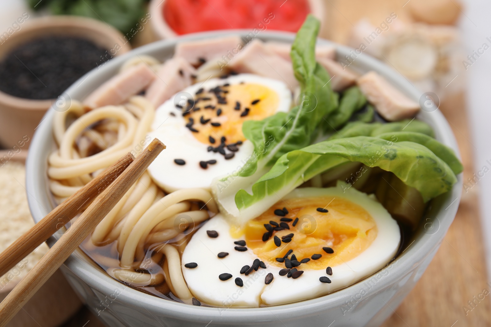 Photo of Bowl of delicious ramen with meat and egg on wooden board, closeup. Noodle soup