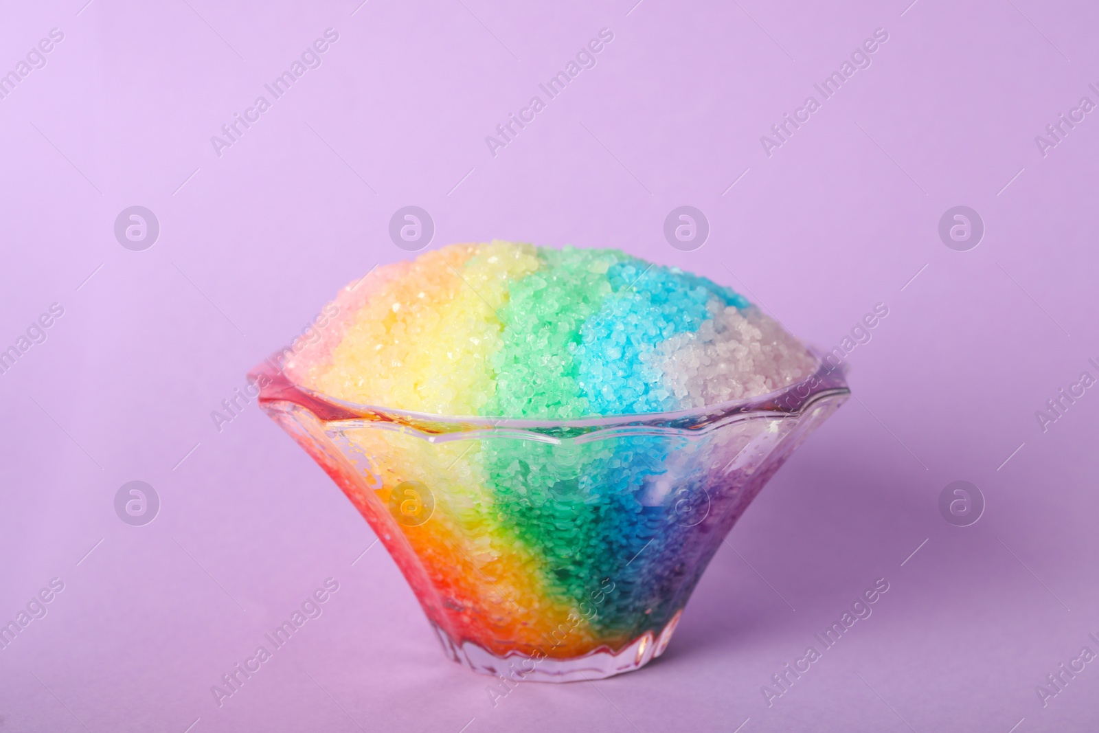 Photo of Rainbow shaving ice in glass dessert bowl on violet background