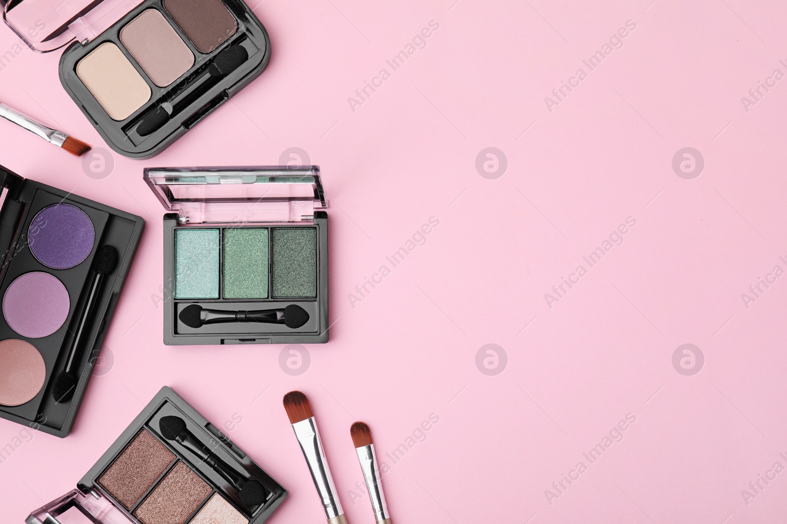 Photo of Beautiful eye shadow palettes and brushes on pink background, flat lay. Space for text