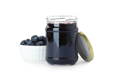 Photo of Jar of blueberry jam and fresh berries on white background