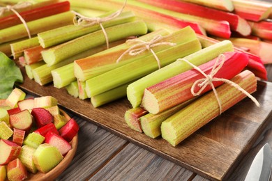 Photo of Many cut rhubarb stalks on wooden table, closeup