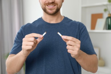 Stop smoking concept. Man holding pieces of broken cigarette at home, closeup