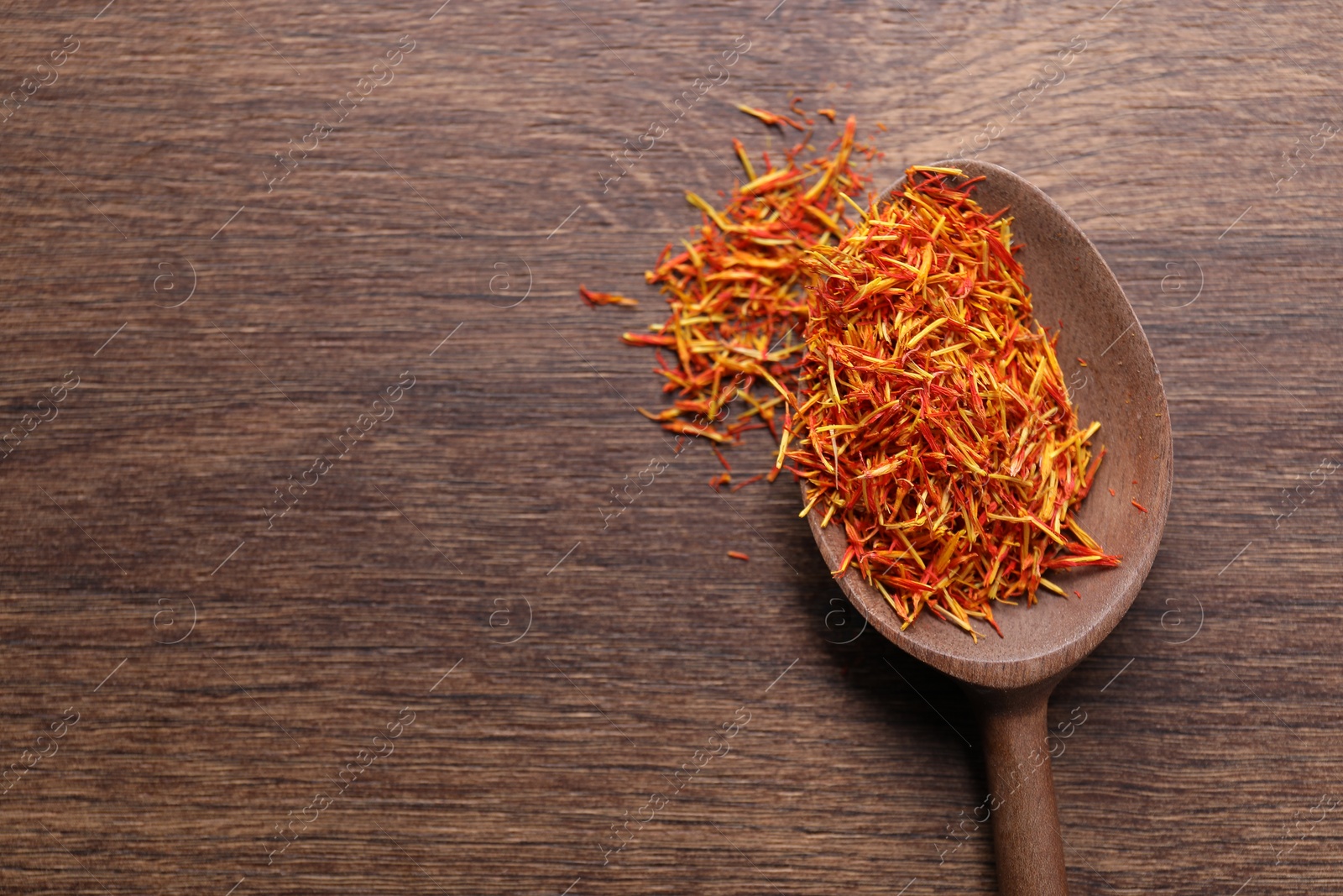 Photo of Aromatic saffron and spoon on wooden table, top view. Space for text