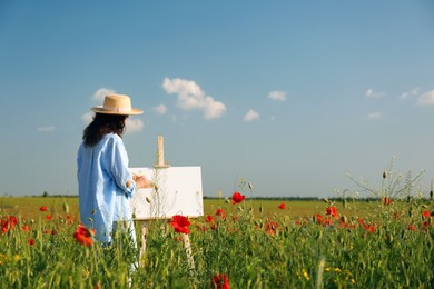 Woman painting on easel in beautiful poppy field